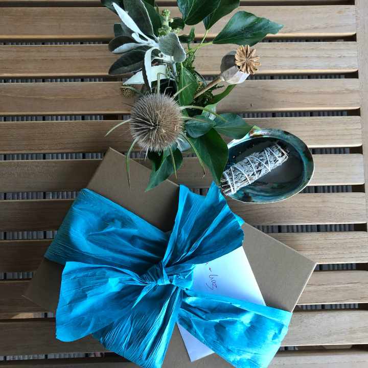 packaged Keepsake copy of a script with a turquoise ribbon in a bow and thistles behind it on a table outdoors