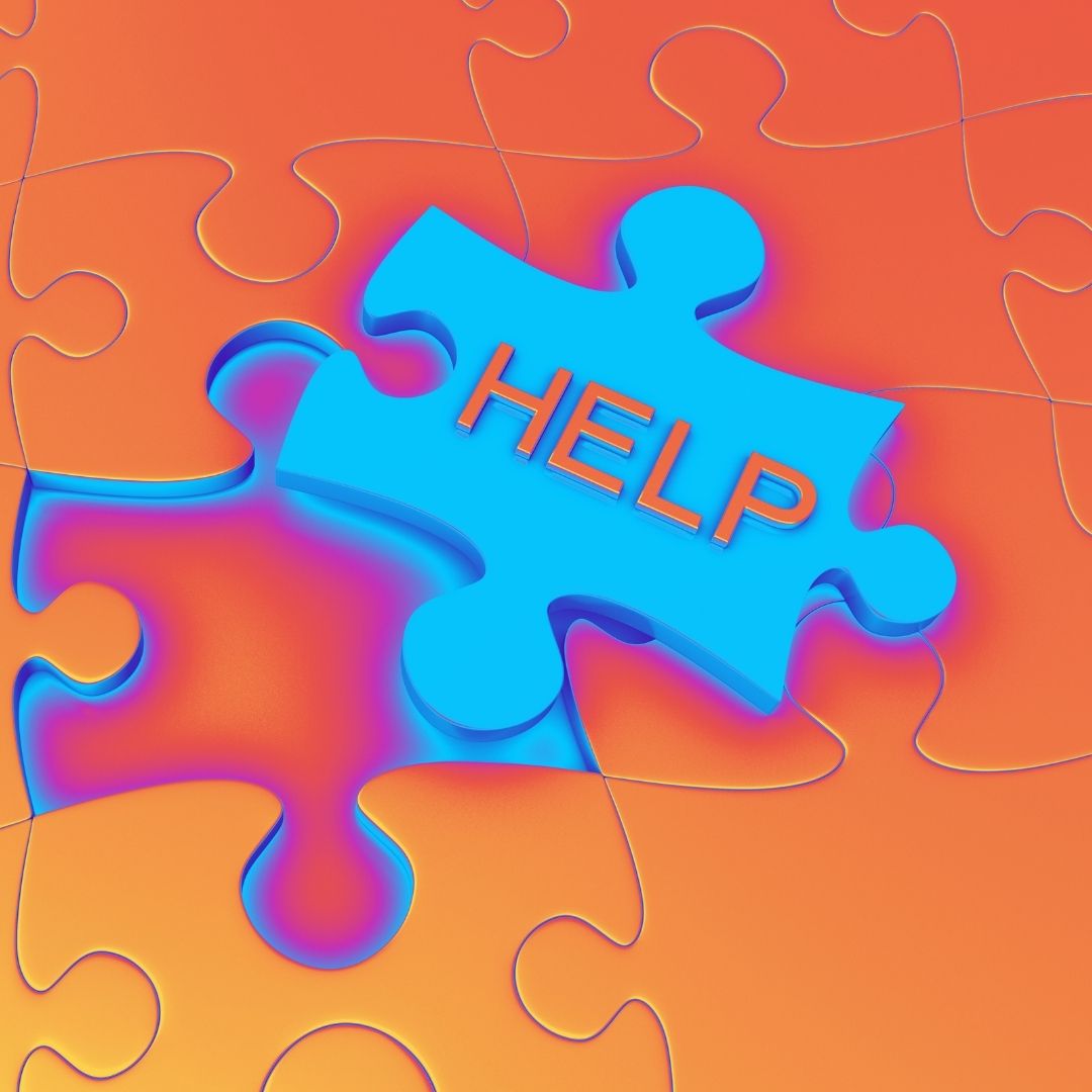 A turquoise jigsaw puzzle piece with 'help' written on it on an orange background.